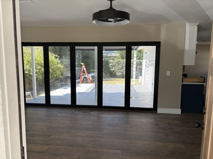Black-framed accordion glass doors opening from living area to backyard patio