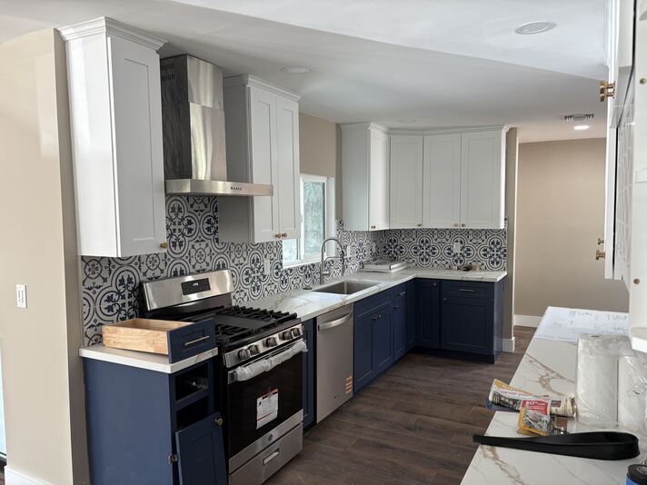 Kitchen gas range, stainless hood, gold hardware, and decorative tile backsplash